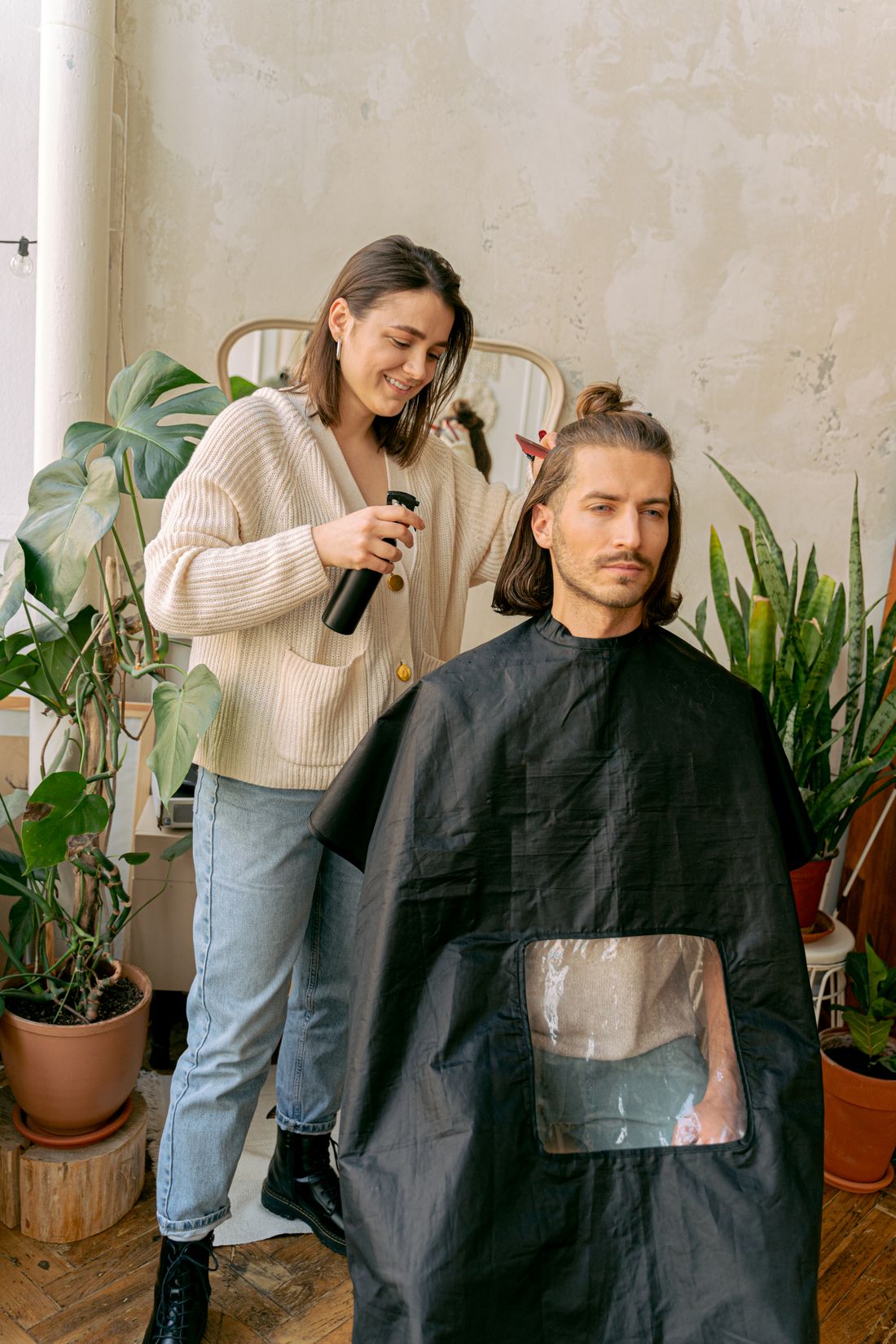 Frisør styler en mands hår i en lys salon med planter