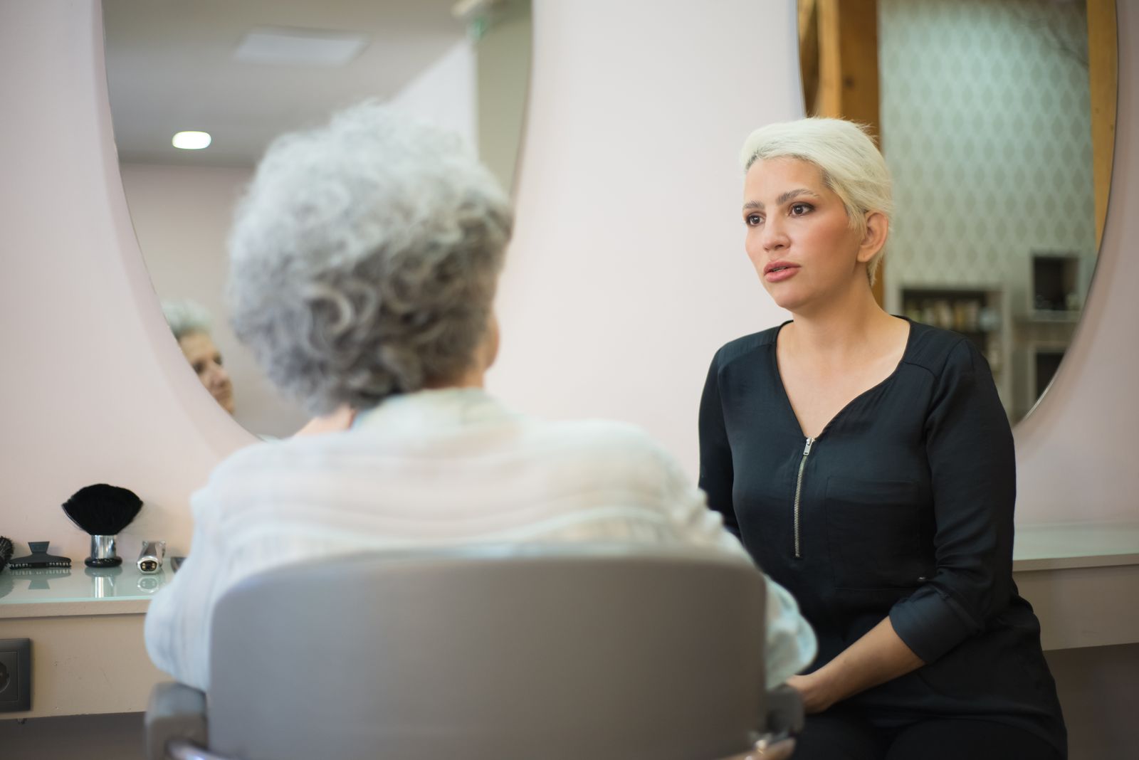Frisør og kunde i samtale foran salonens spejl
